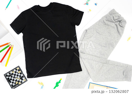 Trendy fashion T-shirt black styled basic clothes and accessories collection on white background. Flat lay, top view. Chess, book, pensils. 132062807