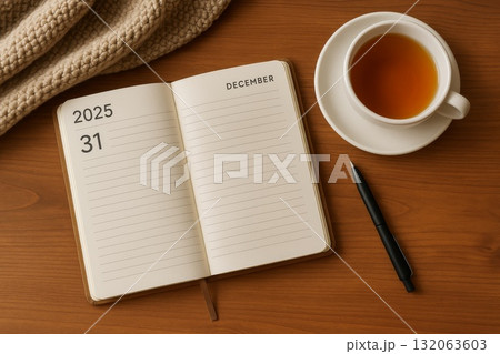Open planner with December 31, 2025 year page, cup of tea, black pen and cozy atmosphere on wooden desk. 132063603