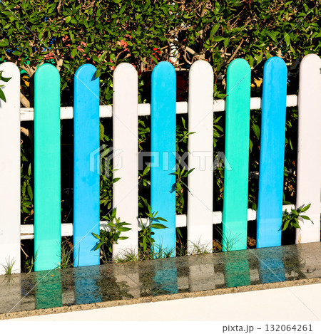 Colorful Wooden Fence Made of White and Blue Planks, Adding a Charming Touch to a Scenic Outdoor Setting, Perfect for Coastal or Beachside Themes Colorful Wooden Fence Made of White and Blue Planks, Adding a Charming Touch to a Scenic Outdoor Setting, Perfect for Coastal or Beachside Themes 132064261