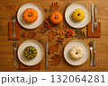 Mini pumpkins on plates with cutlery napkins autumn leaves and berries on wooden table flat lay composition. 132064281