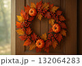 Autumn wreath with pumpkins, colorful leaves, and red berries on wooden door, perfect for seasonal decoration. 132064283