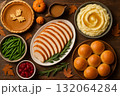 Thanksgiving dinner with turkey, mashed potatoes, green beans, cranberry sauce, dinner rolls, and pumpkin pie on wooden table. 132064284