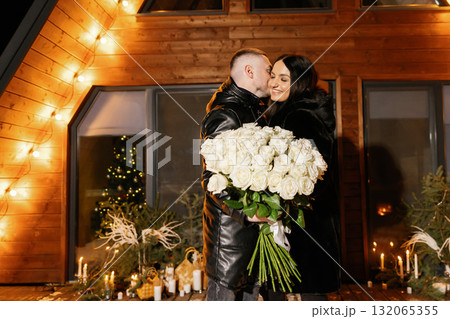 Man whispering to woman holding large bouquet of white roses Man whispering to woman holding large bouquet of white roses 132065355