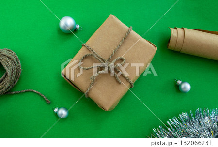 New Year holiday background. Gift, twine and paper, Christmas balls and tinsel on a green background. New Year holiday background. Gift, twine and paper, Christmas balls and tinsel on a green background. 132066231
