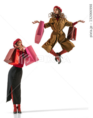 Stylish woman jumping with shopping bags expressing elegance and retail joy 132066998