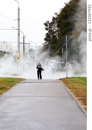 Solitary figure walking through urban steam on wet path - moody city morning Solitary figure walking through urban steam on wet path - moody city morning 132067092