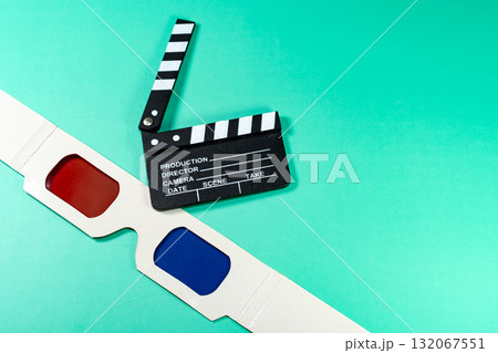 A cinematic composition featuring a clapperboard and 3D glasses against a vibrant, teal background, perfect for movie and cinema themes. 132067551