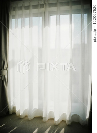 Sheer grey curtains gently sway as bright sunlight streams through a large window, creating a warm and inviting atmosphere in the room during morning hours Generative AI Sheer grey curtains gently sway as bright sunlight streams through a large window, creating a warm and inviting atmosphere in the room during morning hours Generative AI 132067626