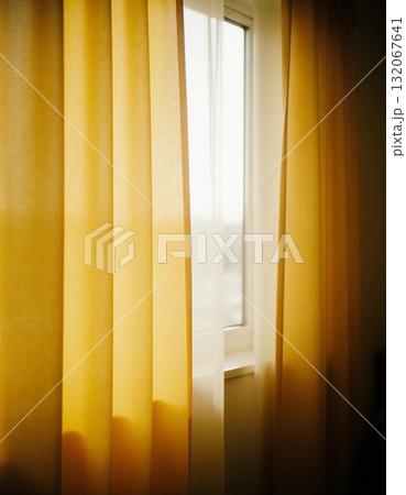 Bright yellow curtains drape elegantly by a window, softly filtering golden sunlight into the room in the morning and creating a cheerful, inviting atmosphere Generative AI 132067641