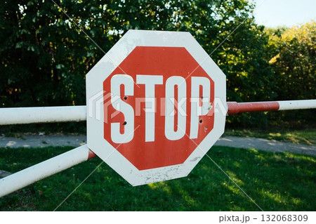 Close-up of red stop sign on barrier on sunny summer day Close-up of red stop sign on barrier on sunny summer day 132068309