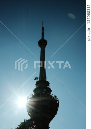 Silhouette of TV tower Iriki Venac at Fruska Gora with bright sun rays shining behind the structure. Destroyed by NATO missile during the Yugoslav war, standing above forest trees 132068315