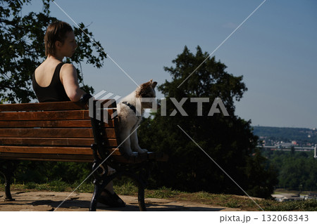 Smiling young woman with her red merle border collie puppy sitting on a bench in Kalemegdan Fortress, Belgrade, with city view in background Smiling young woman with her red merle border collie puppy sitting on a bench in Kalemegdan Fortress, Belgrade, with city view in background 132068343