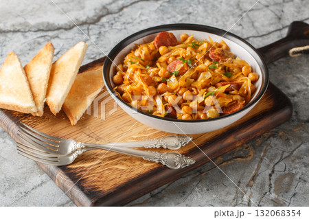 Spanish vegetable stew with cabbage, chickpeas, chorizo and paprika close-up in a plate. Horizontal 132068354