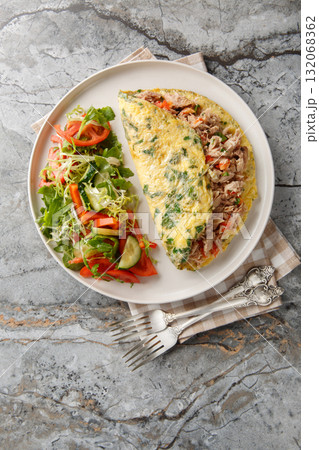 Breakfast Omelet with canned tuna and fresh vegetables salad closeup on the plate. Vertical top view Breakfast Omelet with canned tuna and fresh vegetables salad closeup on the plate. Vertical top view 132068362