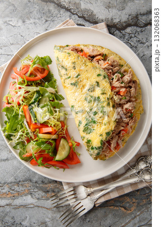 Spanish tuna omelette with vegetable salad close-up in a plate. Vertical top view Spanish tuna omelette with vegetable salad close-up in a plate. Vertical top view 132068363