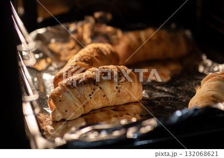 Golden Puff Pastries and Croissants Baking on Foil-Lined Tray in Oven 132068621