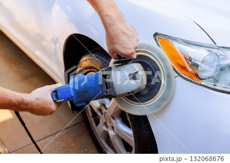 Worker use buffer polisher on white car in driveway, showcasing car detailing skills Worker use buffer polisher on white car in driveway, showcasing car detailing skills 132068676