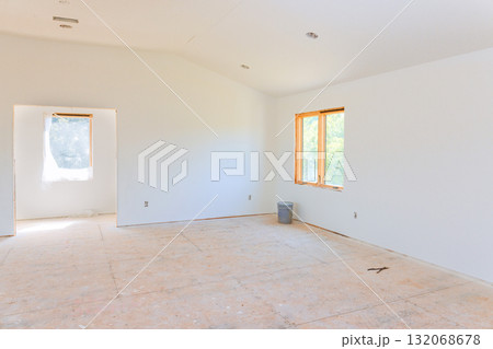 Bright room with bare walls floors, large windows, waste bin, ongoing renovations. Bright room with bare walls floors, large windows, waste bin, ongoing renovations. 132068678