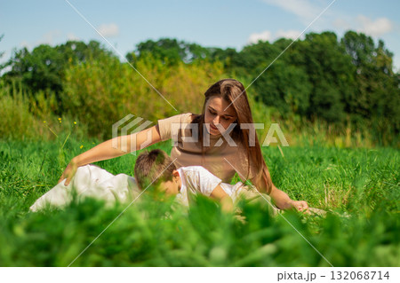 Mother with kid having fun in public green park. Happy mom laughing together with son. Quality leisure time outside. 132068714