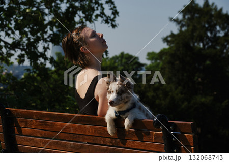 Young woman sits on a bench in Kalemegdan Fortress with her border collie puppy, enjoying the view of Belgrade. Travel with pet concept Young woman sits on a bench in Kalemegdan Fortress with her border collie puppy, enjoying the view of Belgrade. Travel with pet concept 132068743