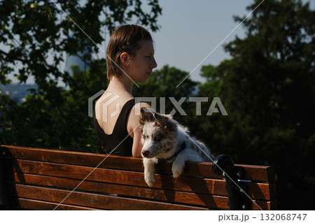 Young woman sits on a bench in Kalemegdan Fortress with her border collie puppy, enjoying the view of Belgrade. Travel with pet concept Young woman sits on a bench in Kalemegdan Fortress with her border collie puppy, enjoying the view of Belgrade. Travel with pet concept 132068747