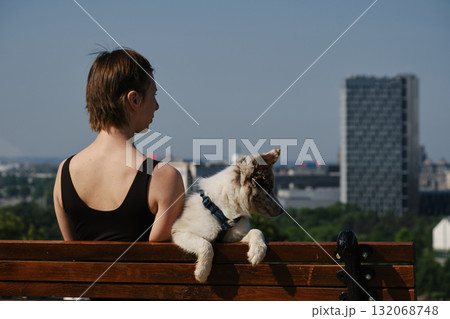 Young woman sits on a bench in Kalemegdan Fortress with her border collie puppy, enjoying the view of Belgrade. Travel with pet concept Young woman sits on a bench in Kalemegdan Fortress with her border collie puppy, enjoying the view of Belgrade. Travel with pet concept 132068748