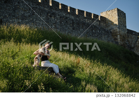 Young woman hugs and kisses red merle Border Collie puppy while sitting on stone ledge near Kalemegdan fortress wall Young woman hugs and kisses red merle Border Collie puppy while sitting on stone ledge near Kalemegdan fortress wall 132068842