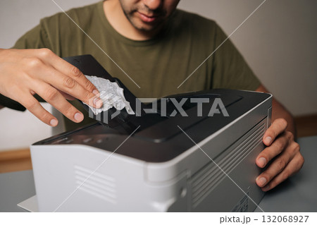 Cropped shot of technician cleaning printer with cloth, performing routine maintenance on essential office equipment, ensuring smooth operation and preventing malfunctions on isolated background 132068927