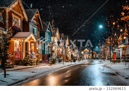 Snowy street with Christmas lights on houses and trees at night. 132069613