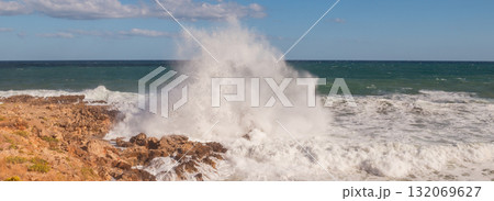 Powerful surf hitting rocks emerald blue sea white foam and clear sky. 132069627