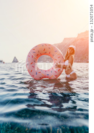 Woman, Sea, Inflatable. Joyful woman in bikini holding a donut swim ring in clear sea water, copy space. 132071054