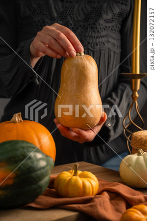 Orange, green and white squashes, female hands holding pumpkin, rustic moody background, autumn concept Orange, green and white squashes, female hands holding pumpkin, rustic moody background, autumn concept 132072157