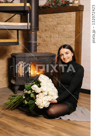 Woman holding large bouquet of white roses near fireplace 132072425
