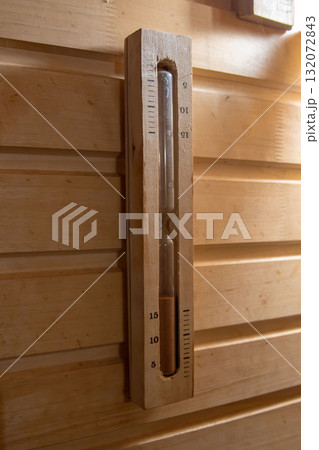 Wooden hourglass sand timer on a rustic sauna wall 132072843
