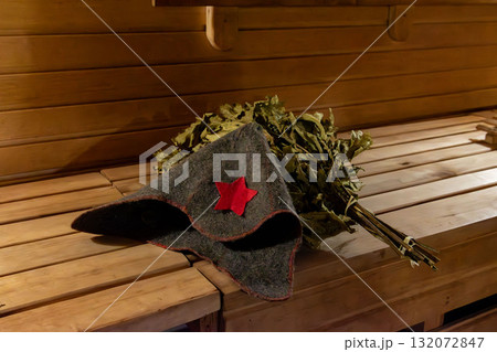 Soviet-style hat and bath broom in a rustic sauna 132072847