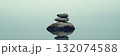 Zen stone cairn on tranquil lake with misty horizon and peaceful reflection 132074588