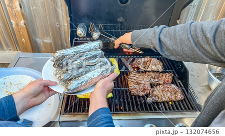 Grilling delicious steaks and wrapped vegetables on barbecue, showcasing vibrant outdoor cooking experience with friends and family gathering Grilling delicious steaks and wrapped vegetables on barbecue, showcasing vibrant outdoor cooking experience with friends and family gathering 132074656