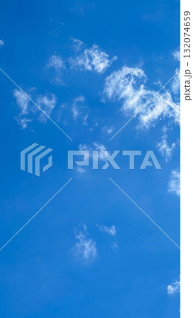 Bright blue sky with fluffy white clouds scattered across the expanse, creating a serene and tranquil atmosphere for outdoor scenes 132074659