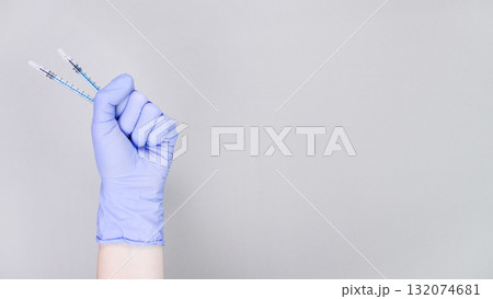 Gloved hand holding two syringes, symbolizing flu vaccination, with a soft gray background emphasizing health and wellness concepts Gloved hand holding two syringes, symbolizing flu vaccination, with a soft gray background emphasizing health and wellness concepts 132074681