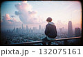 Young man watching city sunset from rooftop edge 132075161