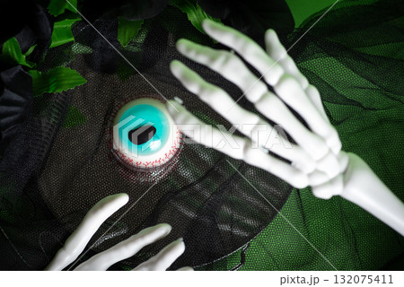 Skeleton hands displaying an eerie blue eyeball on a dark layer Skeleton hands displaying an eerie blue eyeball on a dark layer 132075411