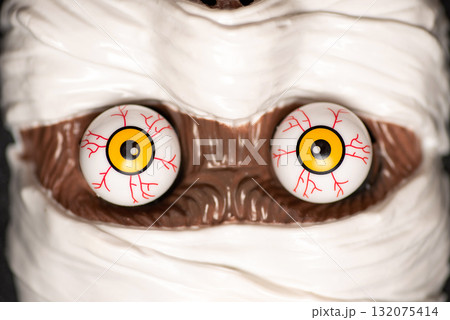 Close-up of a mummy's face with striking eyes and white bandages Close-up of a mummy's face with striking eyes and white bandages 132075414
