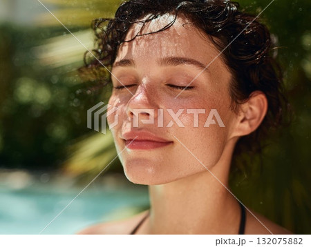 Woman with closed eyes enjoys poolside sun, showcasing smooth skin and wet hair. Perfect for summer beauty and relaxation themes. 132075882