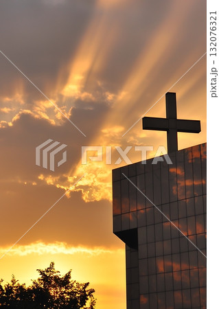 Church steeple with a cross on top and a sun shining on it 132076321
