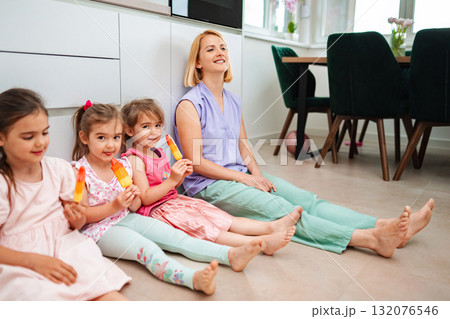 Four joyful girls and a woman enjoy treats at home Four joyful girls and a woman enjoy treats at home 132076546