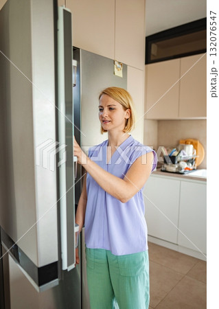 Woman exploring fridge while cooking in modern kitchen Woman exploring fridge while cooking in modern kitchen 132076547