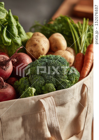 Reusable mesh grocery bag filled with assorted fresh fruits and vegetables 132076887