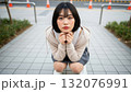 街の路上でしゃがみこみ、こちらをじっと見つめる女性 132076991