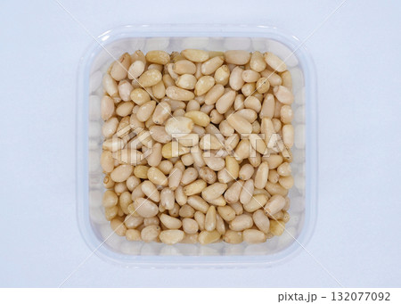 A plastic container filled with pine nuts 132077092