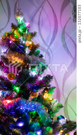 Brightly decorated Christmas tree with colorful lights and ornaments indoors. Festive holiday atmosphere and New Year mood Brightly decorated Christmas tree with colorful lights and ornaments indoors. Festive holiday atmosphere and New Year mood 132077103